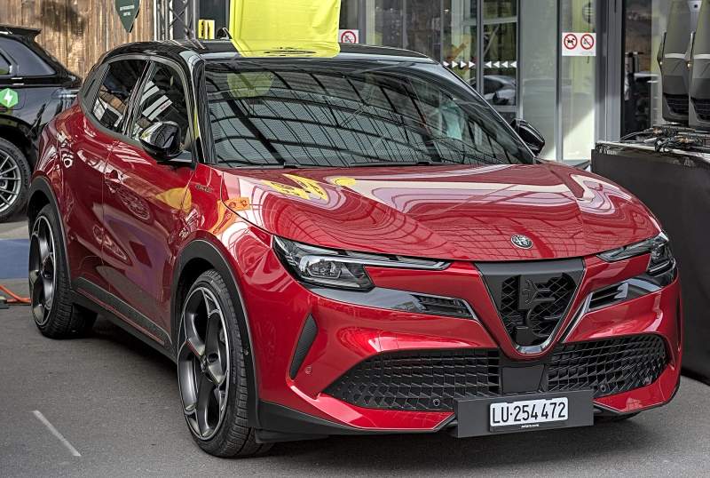 Czerwona Alfa Romeo Junior w elektrycznej wersji Veloce, ujęcie od przodu w trzech czwartych